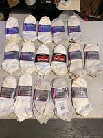 48 pairs of new mostly white Spalding socks laid out partly folded showing packaging and labeling