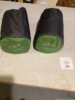 Two black carry bags containing the sleeping mats placed on a table.