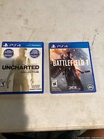 Shows both game cases for Uncharted The Nathan Drake Collection and Battlefield 1 for PS4.