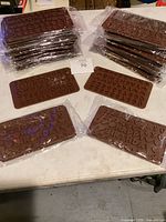 Multiple stacks of brown silicone molds in clear packaging showing alphanumeric characters and symbols