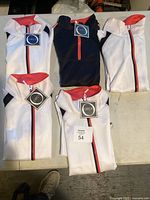 Five folded women's jackets laid out on a table, four white and one black, all with visible Orly tags.