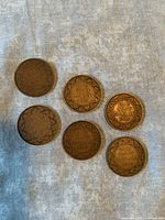 Six antique Canadian one cent coins on fabric background, showing front side with wreath design and text 'One Cent Canada'. Coins vary slightly in patina and wear.