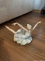 Front angle showing ballerina lying on floor with extended arms and leg.