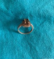 Ring standing upright showing the rectangular smokey quartz center stone, surrounded by small clear gemstones on a 925 sterling silver band.