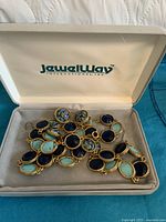 Gold-tone necklace and earrings set inside JewellWay branded display box on fabric surface.