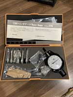 Complete Mitutoyo Series 526 bore gage set including dial gauge, six metal attachments in varying sizes, and instructional manual in orange-black case.