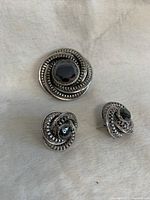 Front view of vintage Danecraft brooch and matching earrings showing circular braided silver metal and hematite stone centers