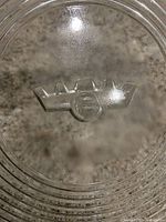 Close-up of embossed Frigidaire crown logo on the base of the glass tray.