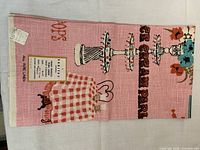 Full view of folded pink Irish linen tea towel showing ice cream parlor design and original label.