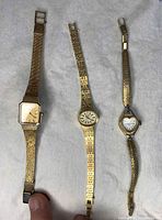 Top view of three vintage ladies' gold-tone wristwatches displaying faces and bands.