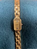 Full view of the gold tone Renaissance wristwatch showing rectangular gold dial, two diamond-like hour markers, and linked bracelet.