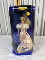 Full front view of Barbie doll in original box showing pink satin gown, fur wrap, and pearl necklace with yellow price sticker on packaging.