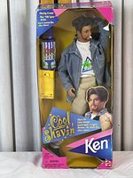 Front view of Ken doll in original packaging with denim jacket, colorful shirt, and included shaving accessories.