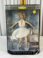 Front view of Barbie Marilyn Monroe doll in pleated white dress with original packaging, showing details of doll and box front.