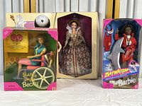 Image showing the three Barbie dolls in their original boxes: 'Sharing Smiles Becky' in a wheelchair, a Barbie dressed in a detailed royal gown, and a Baywatch Barbie in a life jacket.