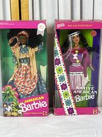 Front view of Native American and Jamaican Barbie dolls in original packaging showing box condition and details of dolls' outfits.