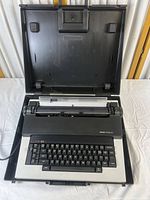 Top-down view of Olivetti Praxis 30 electric typewriter open in case showing keyboard and paper holder.
