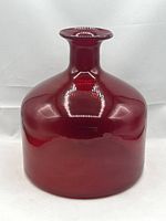 Front view of ruby red glass bottle showing wide body and narrow neck with flared lip