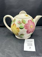 Blue Ridge Pottery teapot with floral design on a black background, clear view of handle, spout, and lid.