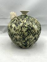 Front view of textured porcelain vase with green glaze and quartz crystal cluster attached near the neck.