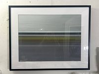 Framed photograph showing horizontal bands of gradient tones with light reflection on plexiglass.