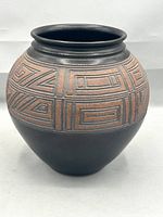 Front view of the vase showing rust-toned geometric incised pattern and matte brown base.