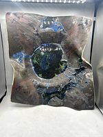 Top view showing the textured, multicolored glaze with blue, green, and black layered over earthy tones on an asymmetrical square-shaped bowl.