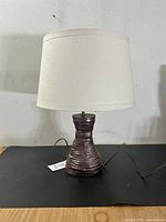 Full view of mid-century pottery lamp showing ceramic ridged and glazed red-brown base with neutral drum shade