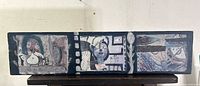 Front view of mixed media wood panel artwork showing three surreal narrative scenes arranged like filmstrip frames, predominantly dark tones with layered collage and paint.