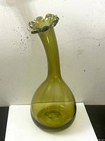Front and side views of the olive green Blenko art glass vase showing bulbous base and ruffled rim.