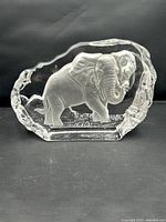 Front view of the clear glass paperweight showing the full etched elephant design within the sculptural glass block.