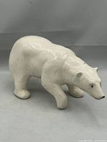 Side view of white glazed pottery polar bear sculpture showing the shape and glaze finish with crazing.