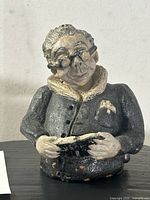 Front view of a 5-inch ceramic sculpture of a bespectacled figure in a textured jacket holding a book.