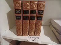 Four volumes upright on a shelf showing spine titles and decorative embossing.