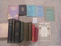 Overview of thirteen esoteric books and one periodical laid out on carpeted floor