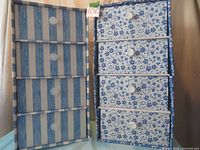 Two cardboard drawer storage units side-by-side; one is blue and white striped, the other white with blue floral pattern, both featuring four drawers each with white knobs.