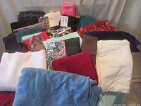 Multiple assorted fabric pieces in various colors, patterns, and materials laid out on a surface.