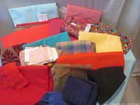 Overview of assorted fabric pieces showing various solid colors and some patterns, folded and stacked