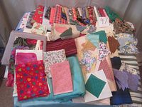 Full overview of assorted fabrics including quilting cotons, wool tartan, and solid pieces arranged flat