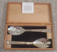 Salad servers in open wooden box showing the embossed salmon designs on the spoon and fork serving utensils.
