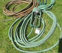 Overview of three garden hoses and one Gilmour oscillating sprinkler laid on grass
