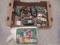 Overview of all items in box including four watering timers, various fittings, and bag of floating row cover fabric