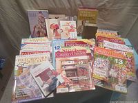Wide view of entire collection showing various sewing and quilting books and magazines arranged on a beige surface.