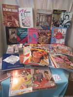 Photo showing multiple vintage and modern sewing books and magazines arranged in rows, featuring Butterick Sewing Book, Creative Journals, Art and Beadweaving books, and multiple Simplicity and Vogue pattern books.