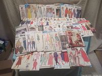 Wide view of the collection of sewing patterns spread out on a table, showing multiple brands and various styles for adults and children.