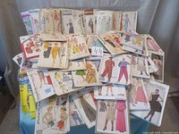 Overall view of assorted sewing patterns stacked showing various brands including Butterick, Simplicity, McCall's, Advance, and others for women and children.