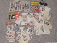 Overview image showing two open stamp albums, loose stamps sorted in piles and envelopes, and a jar containing stamp hinges.