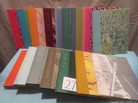 The full 15 volume set arranged in two rows showing the colorful and textured covers with fabric and leather accents.