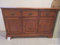 Front view of the hardwood maple buffet cabinet with three drawers and three doors, showing medium wood finish and traditional styling.
