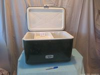 Open cooler showing interior plastic divided compartment with lid showing embossed geometric design.